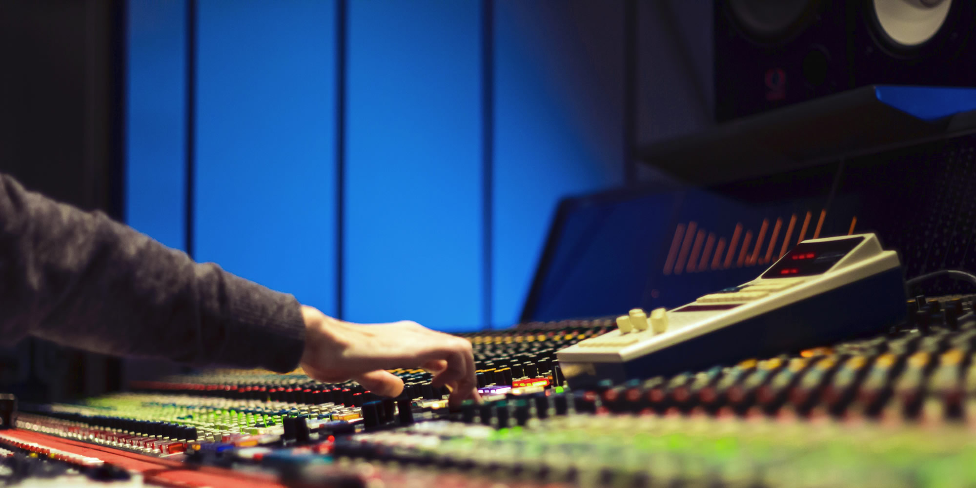 Mammoth Production music studio in Sweden, illustrated by studio mixing console with music producer's hand on console